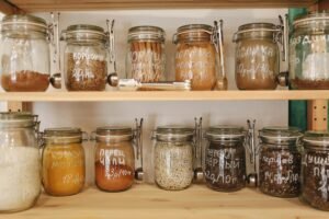 pexels-photo-3735147-3735147 Organized pantry with glass jars holding a variety of spices and ingredients on wooden shelves.