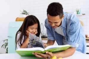 A father and daughter enjoy quality time reading a book together in their modern kitchen.